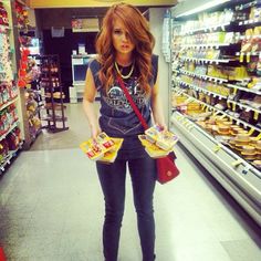 a woman is standing in a grocery store holding some food