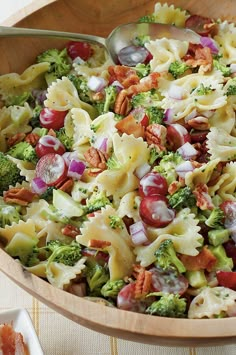 pasta salad with broccoli, red onions and pecans in a wooden bowl