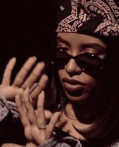 a woman wearing sunglasses and a bandana is holding her hands up to the camera