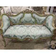 an ornately decorated couch sitting on top of a floor next to pillows and other furniture