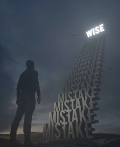 a man standing on top of a hill next to a tall tower with words written in it