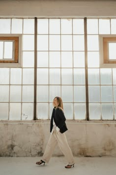 a woman walking in front of large windows