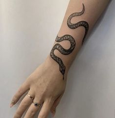 a woman's hand with a snake tattoo on the left wrist and right arm