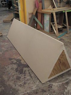 a pile of plywood sitting on top of a floor next to a wooden wall