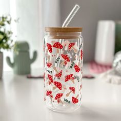 a glass cup with a straw in it sitting on a table next to a potted plant