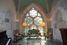 a living room filled with furniture next to a large stained glass window covered in lots of windows