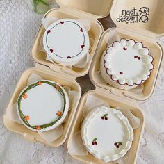 four plastic trays filled with cakes on top of a white cloth covered tablecloth