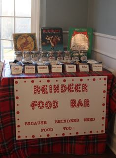 a red and white table topped with food items next to a sign that says reindeer food bar