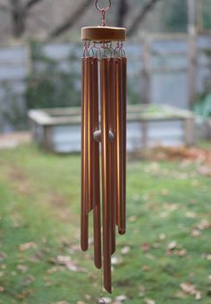 a wind chime hanging from the side of a tree in front of a bench