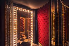 a mirror that has lights on it in front of a red wall and checkered floor