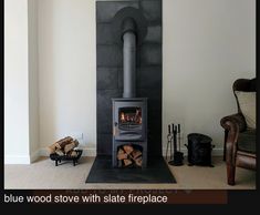 a wood burning stove in a living room next to a chair and firewood logs