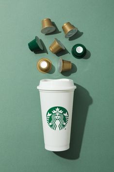 starbucks coffee cup surrounded by other items on green background