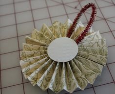 an origami flower with red beads on it