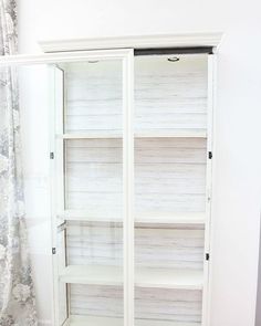 an empty white bookcase in the corner of a room