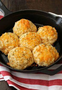 a skillet filled with biscuits on top of a red and white towel