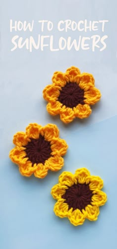 two crocheted sunflowers sitting next to each other on a blue surface