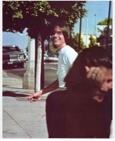 a man walking down the street with his arm around another man's shoulder and smiling