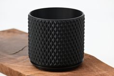 a black vase sitting on top of a wooden table