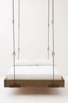 a bed suspended by chains with white sheets