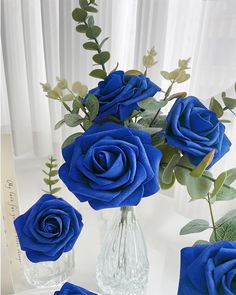 three blue roses in a vase on a table