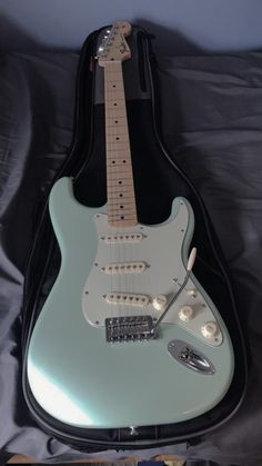 an electric guitar in its case on a bed