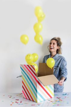 a woman holding a box with balloons coming out of it