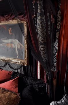 a painting hanging on the wall next to a bed covered in red and black sheets