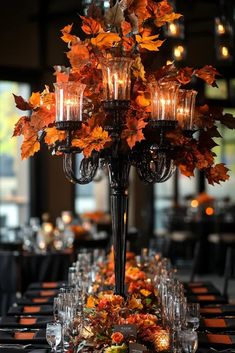 an elegant centerpiece is adorned with candles and fall leaves for a festive touch