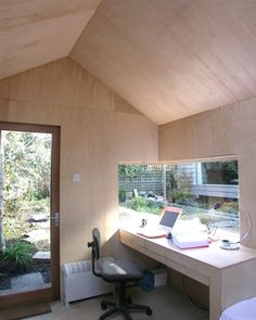 a desk with a laptop on top of it in a room next to a sliding glass door