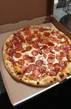 a pepperoni pizza sitting in a box on the counter