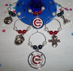 the chicago cubs wine glass charm is hanging from a blue plate with red and white beads