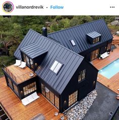 an aerial view of two black houses on a wooden deck with a pool in the background