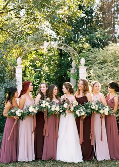 a group of women standing next to each other holding bouquets in their hands and smiling