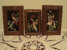 three framed pictures are sitting on a doily