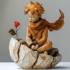 a wooden sculpture of a boy sitting on a rock with a rose in his hand