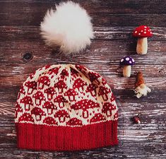 a red and white knitted hat next to mushrooms on a wooden table with other items