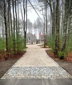 a brick walkway leading to a house in the woods