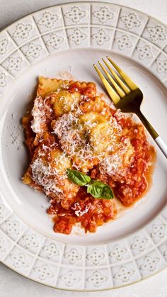 a white plate topped with lasagna covered in sauce and parmesan cheese