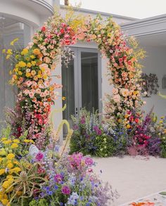 an arch made out of flowers in front of a house