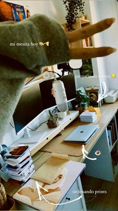 a computer desk with many different items on it and an arrow pointing to the monitor