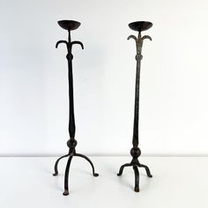 two metal candlesticks sitting next to each other