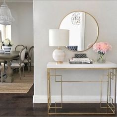 a living room with a table, mirror and lamp in it's centerpiece