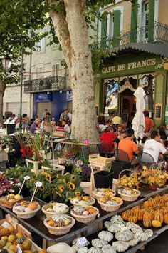 an outdoor market with lots of fruits and vegetables on display in front of the building