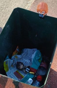 an open trash can on the ground with garbage in it