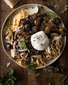 a plate of pasta with mushrooms, cheese and herbs