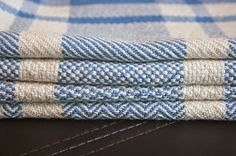 three blue and white checkered towels folded on top of each other, with one folded up