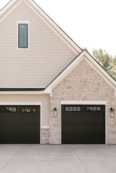 two black garage doors in front of a house