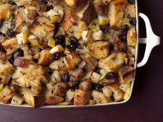 a casserole dish filled with stuffing and vegetables on a wooden counter top,