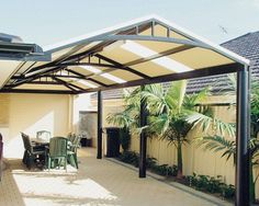 a patio covered in metal and surrounded by palm trees