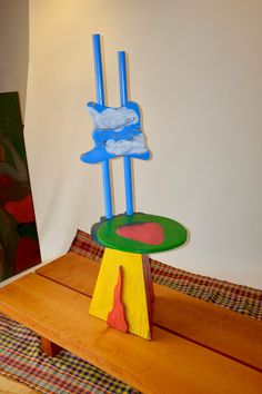 a wooden table topped with a colorful sculpture on top of it's side stand